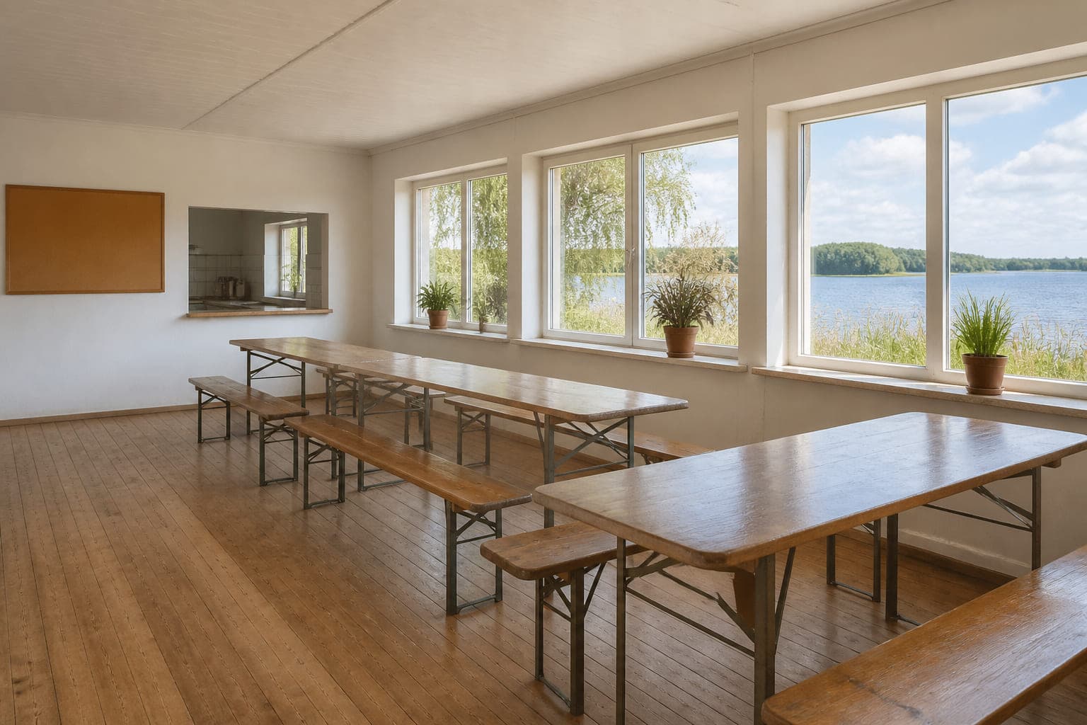 Der helle Vereinsraum mit langen Holztischen und Bänken, großen Fenstern zum See und Pflanzen auf den Fensterbänken.